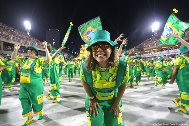 Smiling samba school members in green and yellow waving Brazilian flags