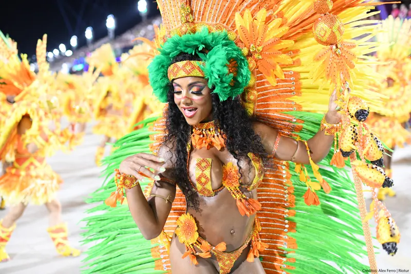 A samba dancer in a bright orange and green feathered costume